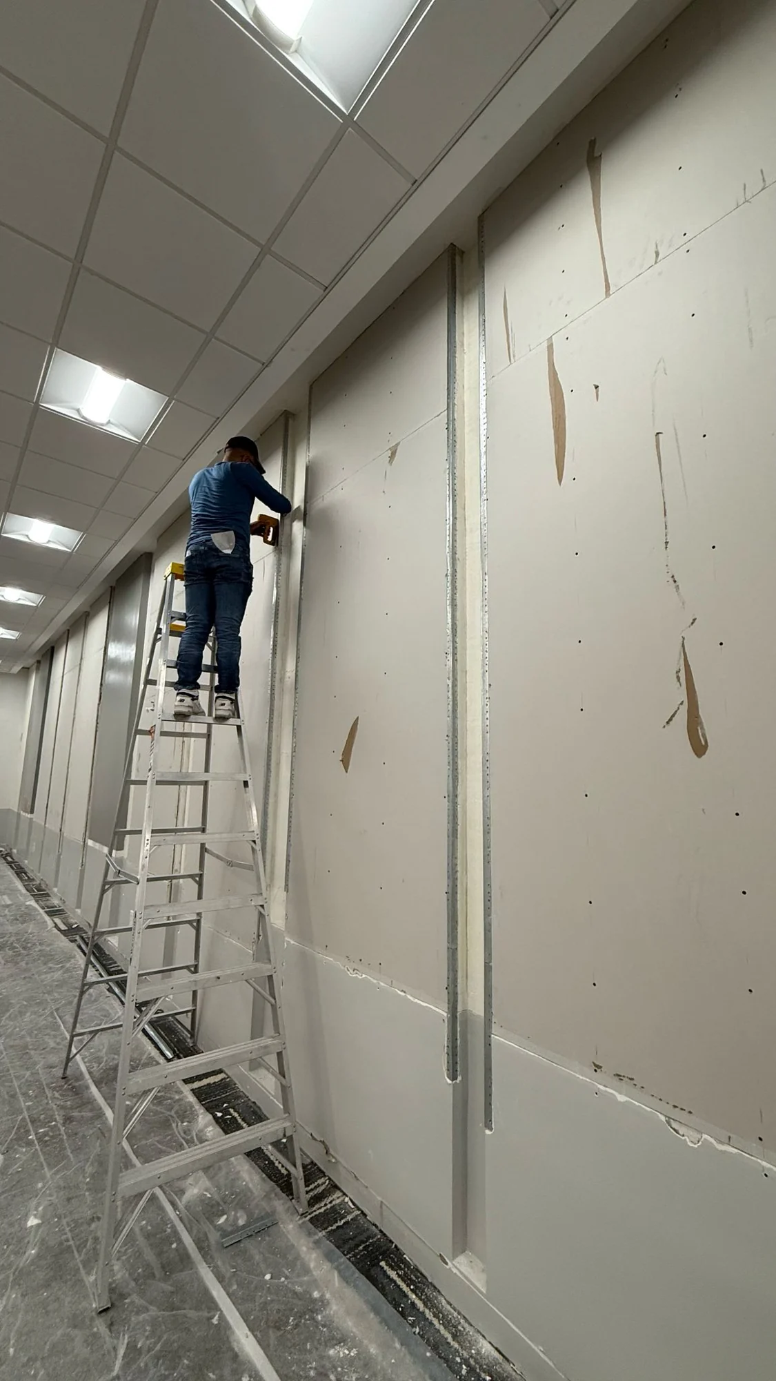 Installer working on the exposed wall surface during preparation · Hotel Alba Tampa, Tapestry Collection by Hilton
