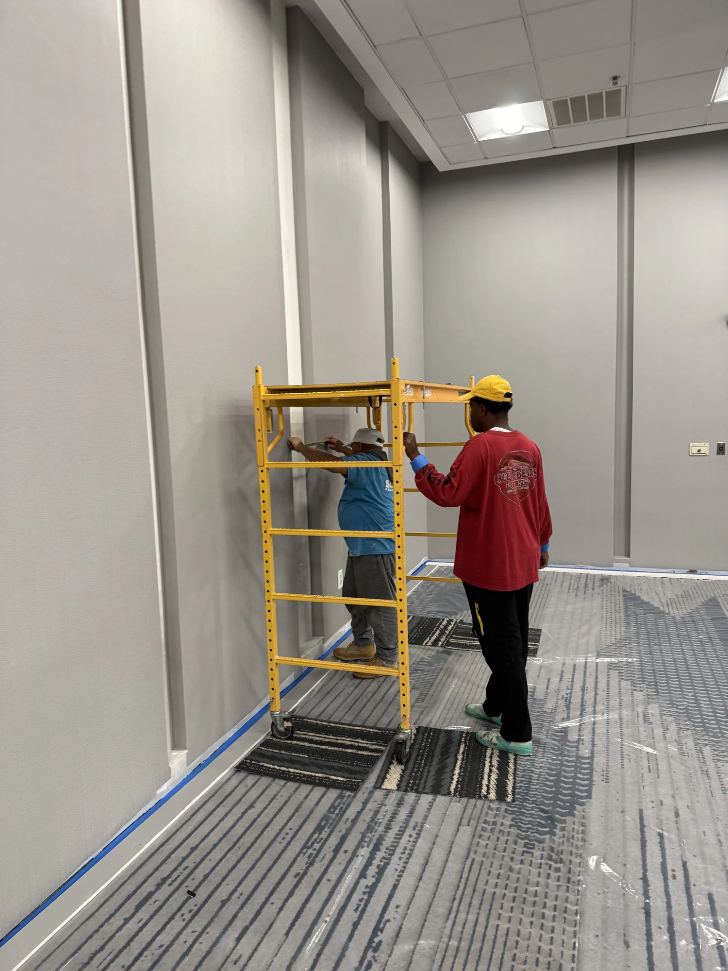 Crew working on wallcovering between vertical trim with protective tape in place · Hotel Alba Tampa, Tapestry Collection by Hilton