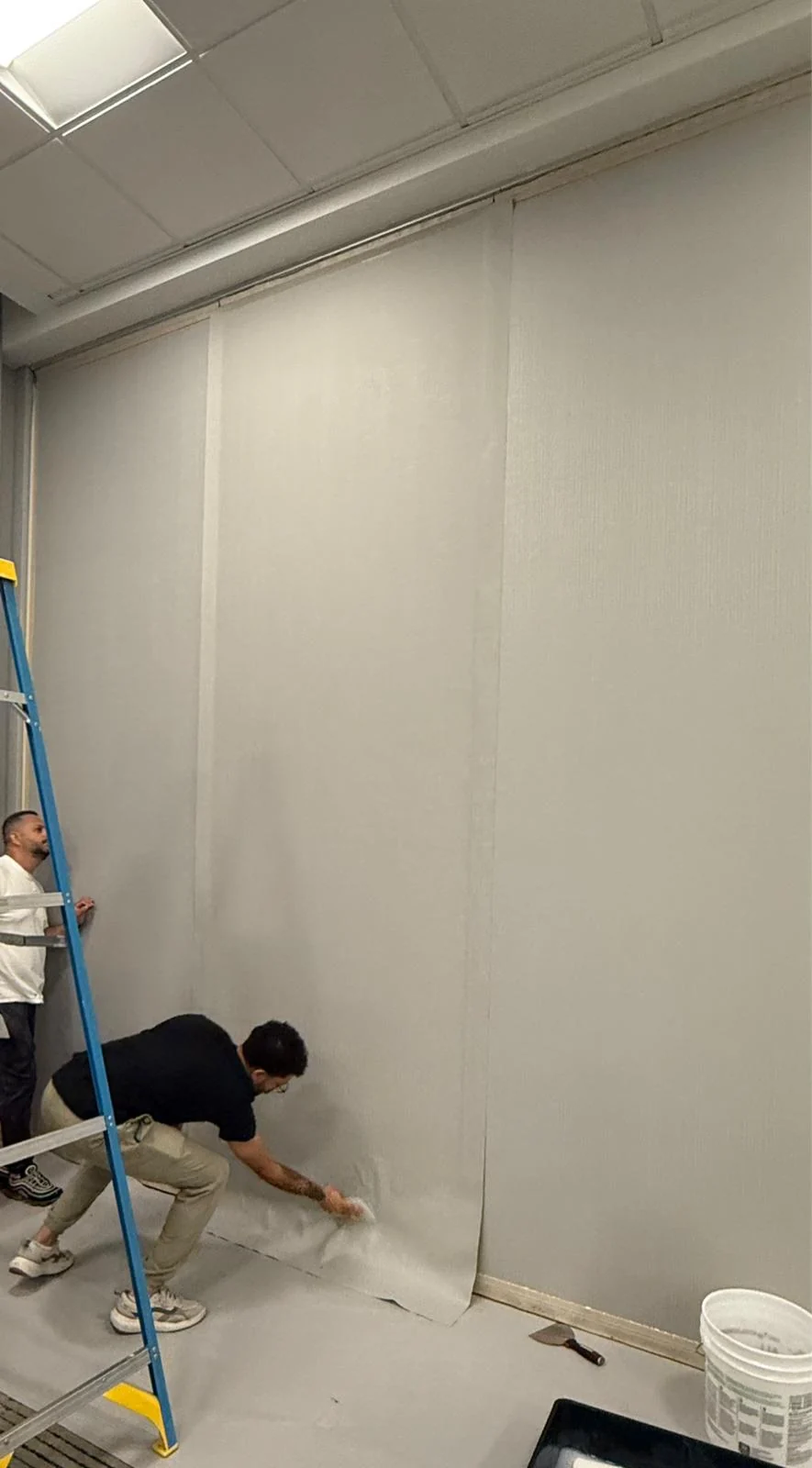 Installer smoothing wallcovering near the base during installation · Hotel Alba Tampa, Tapestry Collection by Hilton