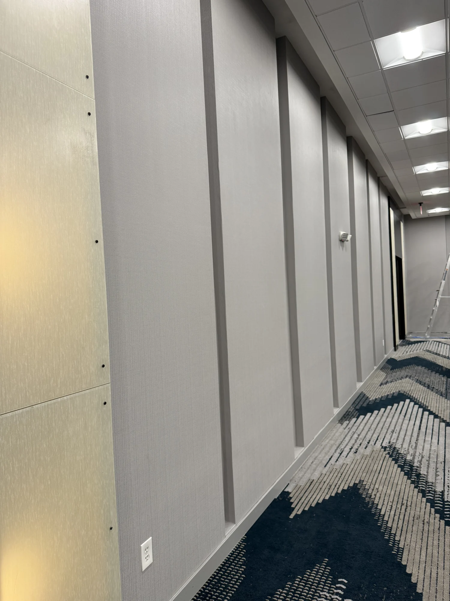 Close view of installed wallcovering and vertical trim while adjacent doorway work remains in progress · Hotel Alba Tampa, Tapestry Collection by Hilton