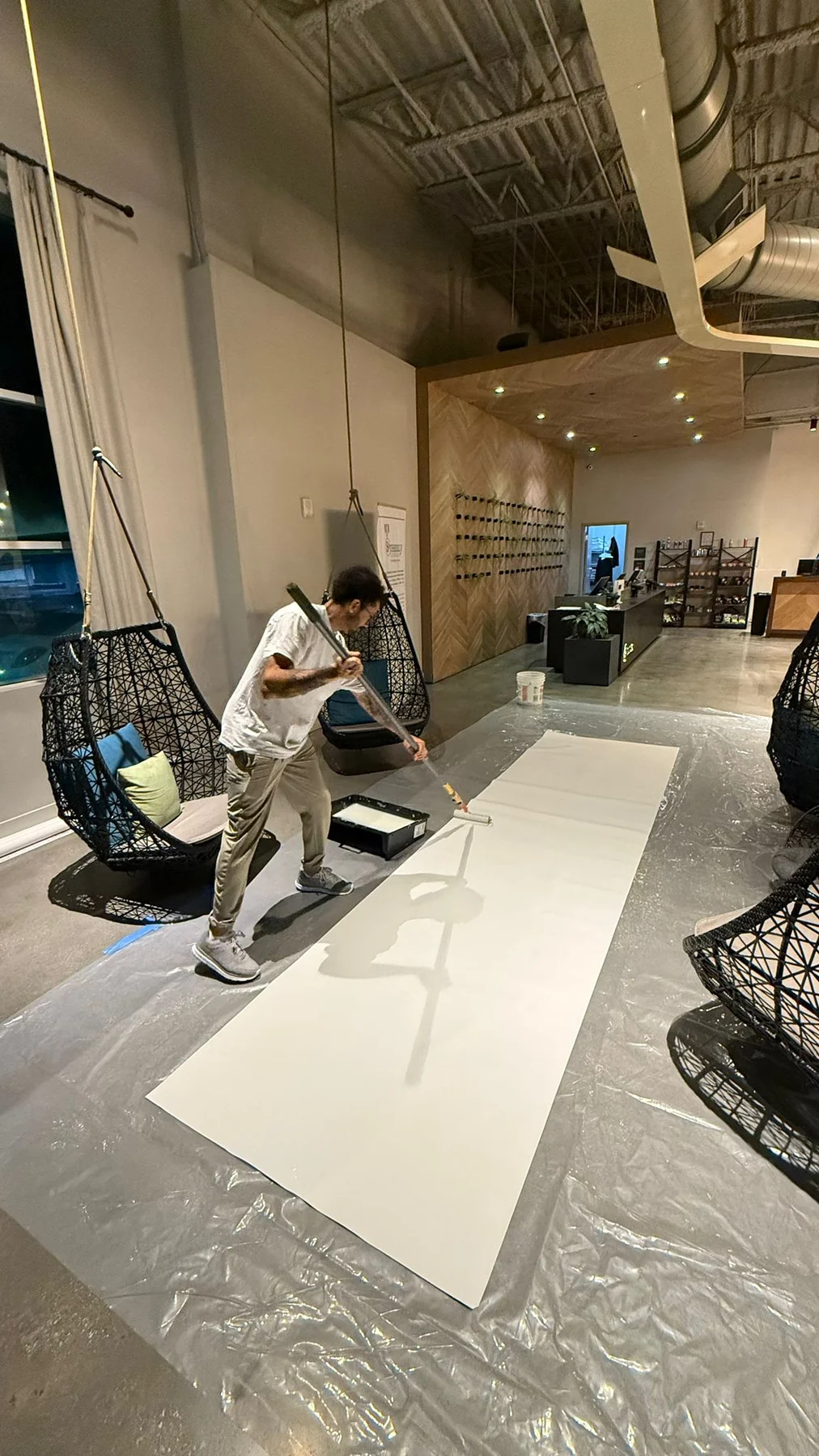 Crew member preparing a length of wallcovering on a protected work surface · Hotel Alba Tampa, Tapestry Collection by Hilton