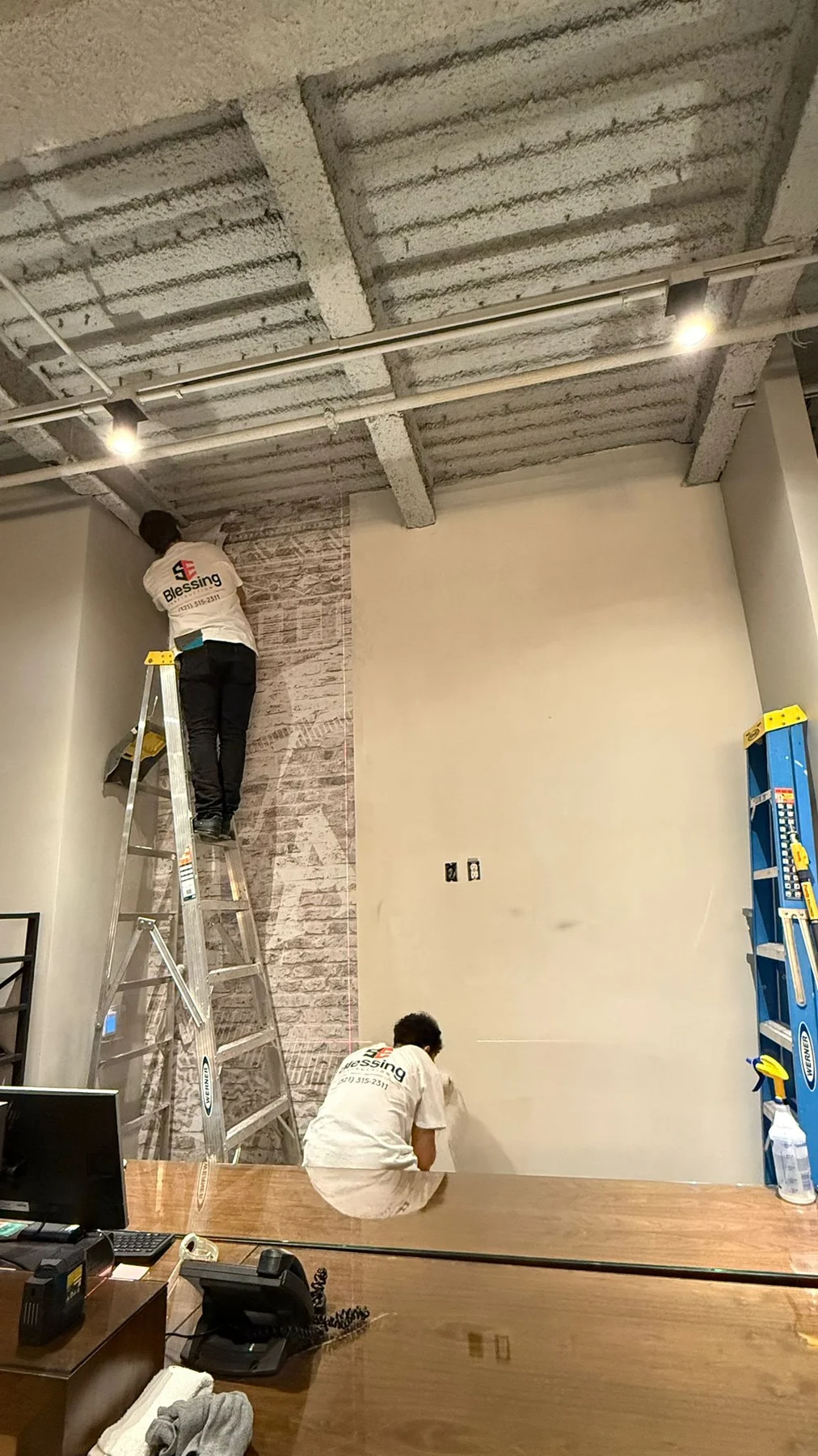 Crew installing the first vertical sections of brick-pattern wallcovering · Hotel Alba Tampa, Tapestry Collection by Hilton