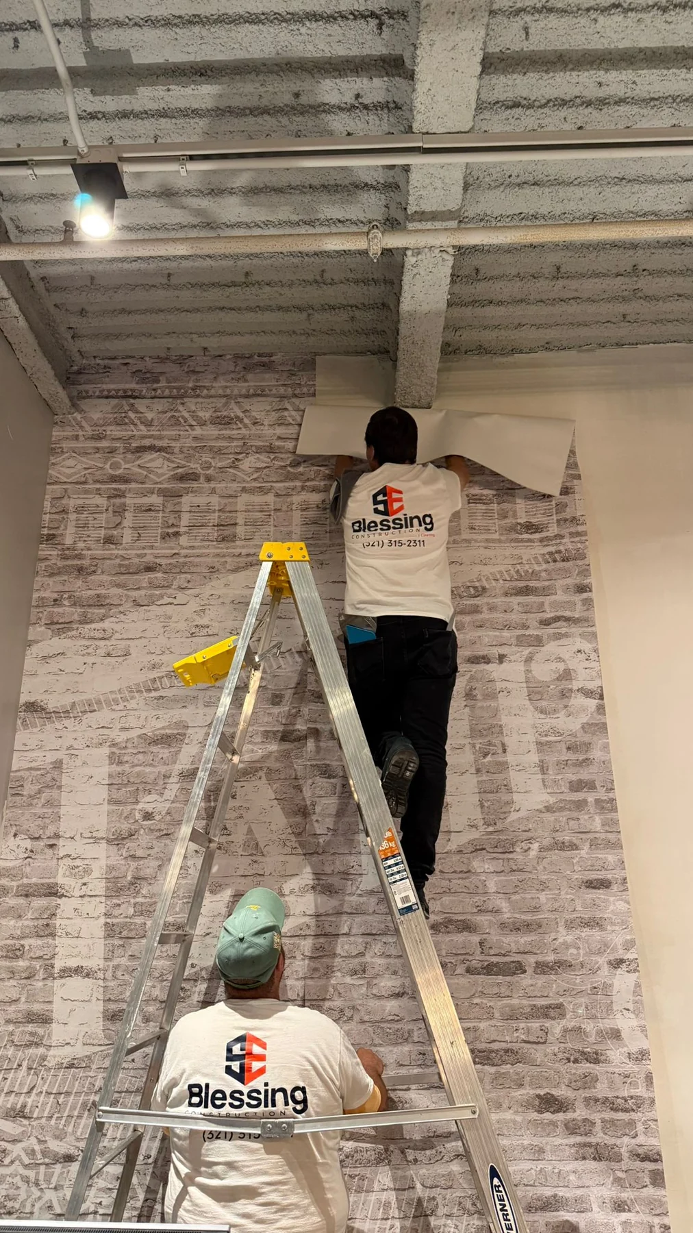 Crew positioning another length of patterned wallcovering on the lobby feature wall · Hotel Alba Tampa, Tapestry Collection by Hilton