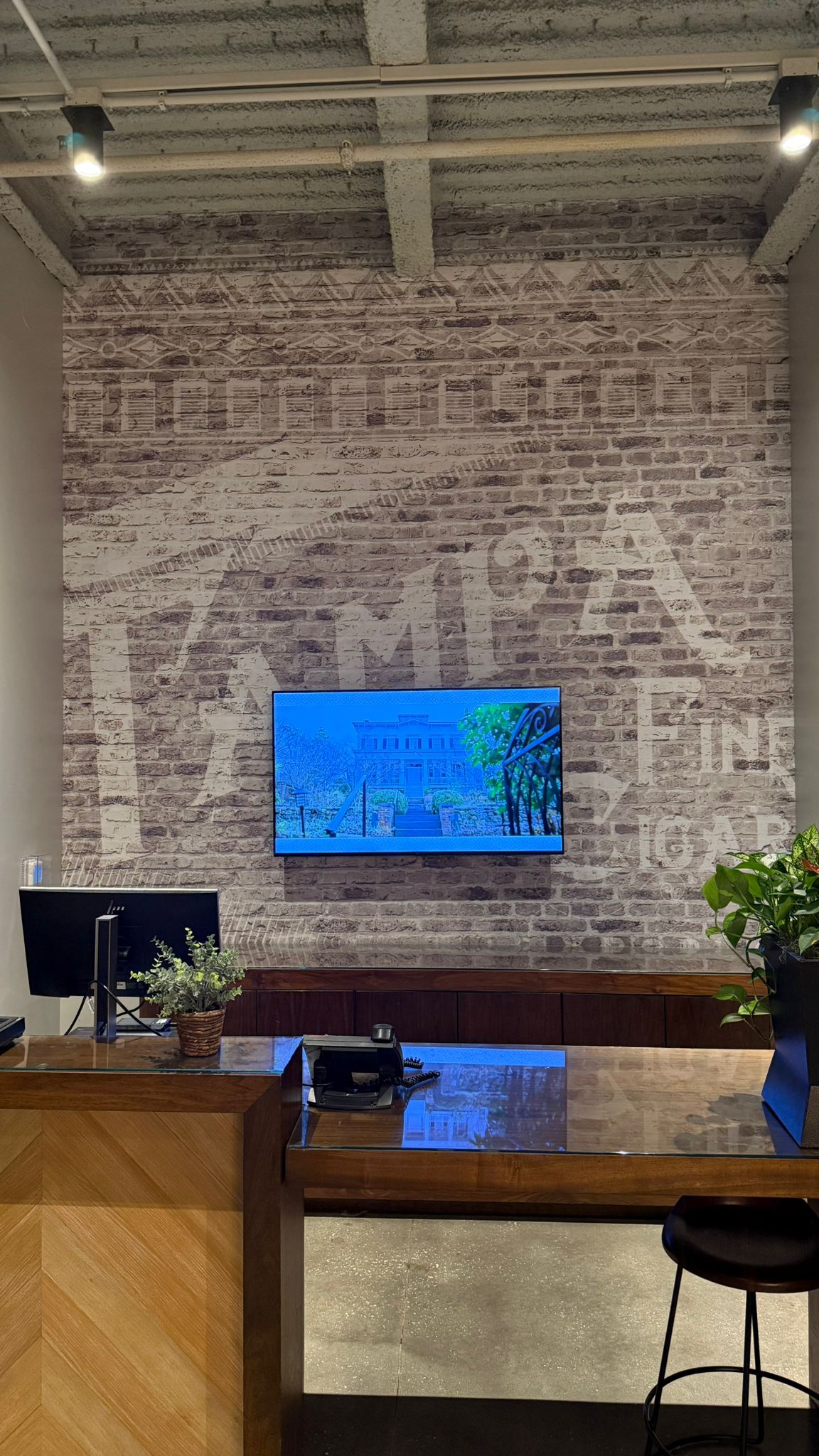 Completed lobby wallcovering behind the television and wood reception counter · Hotel Alba Tampa, Tapestry Collection by Hilton