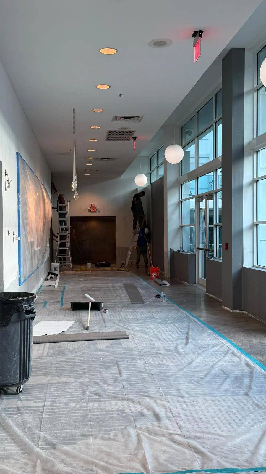 Crew working beside the hallway windows with artwork and existing carpet protected · Hotel Alba Tampa, Tapestry Collection by Hilton