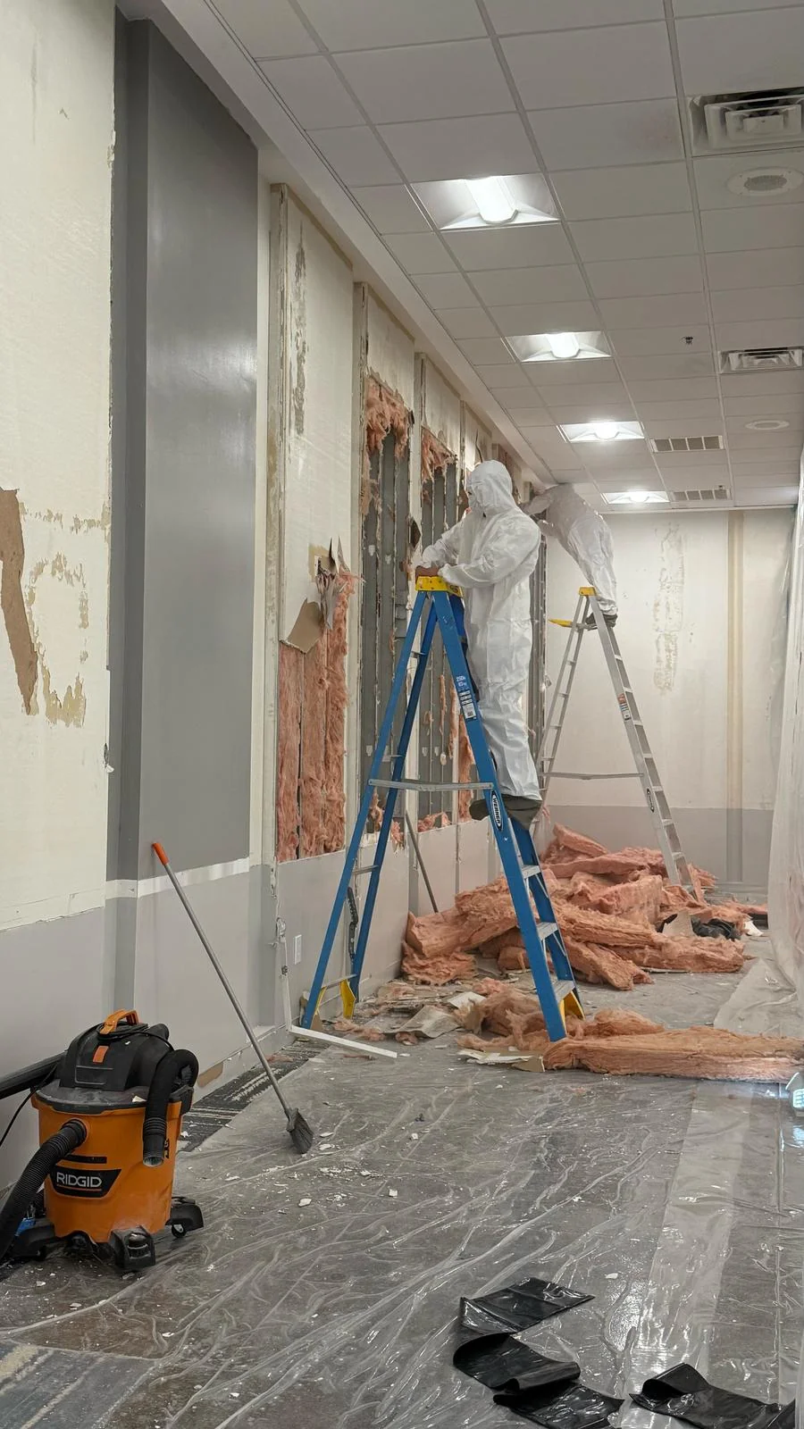 Drywall and insulation removal in progress along the enclosed work area · Tapestry Collection by Hilton