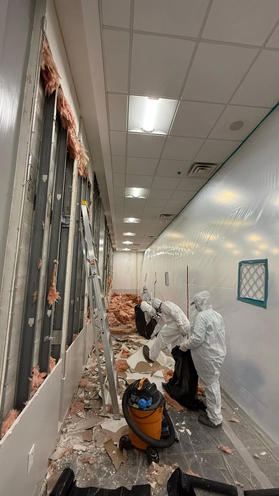 Crew clearing debris along the exposed wall framing · Tapestry Collection by Hilton