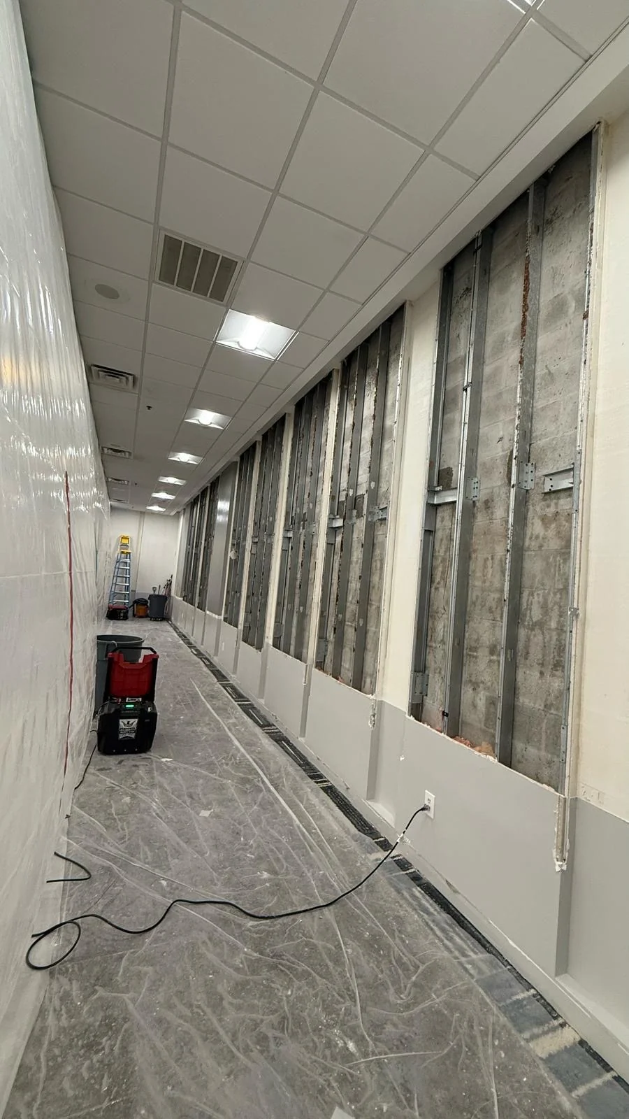 Exposed wall framing after removal, with floor protection and equipment in place · Tapestry Collection by Hilton