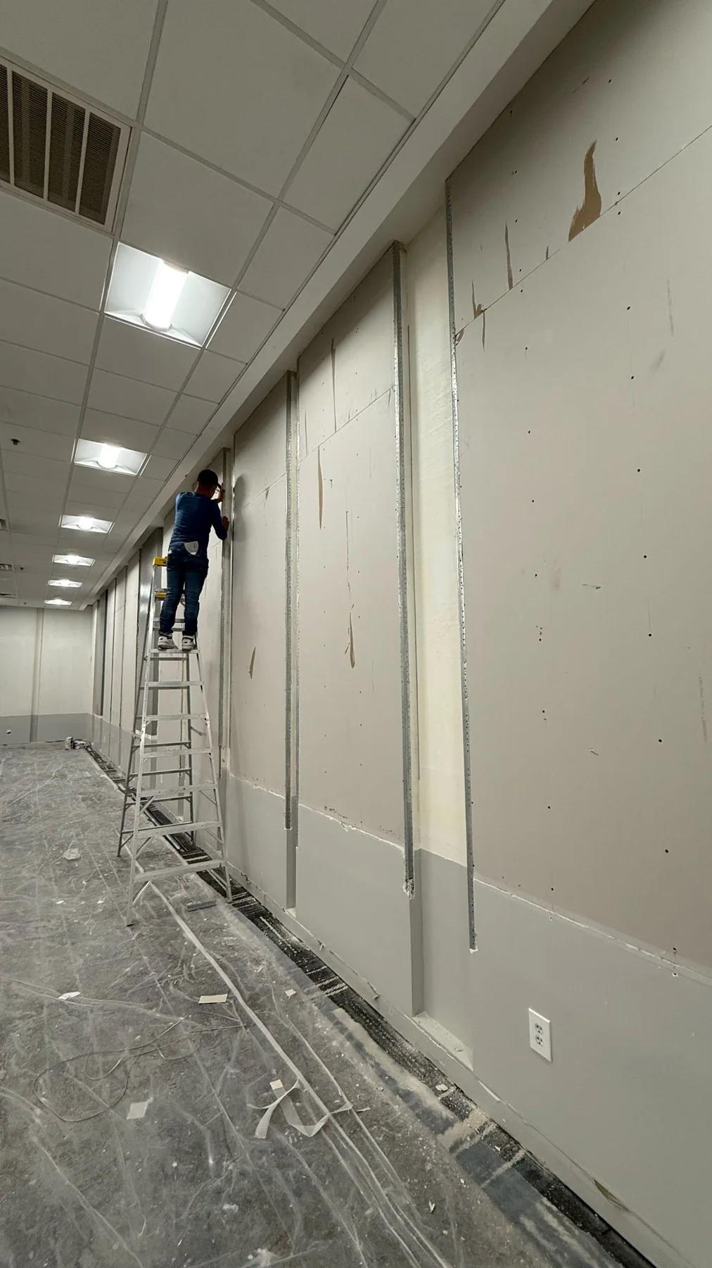 Replacement drywall panels in place while work continues along the wall · Tapestry Collection by Hilton