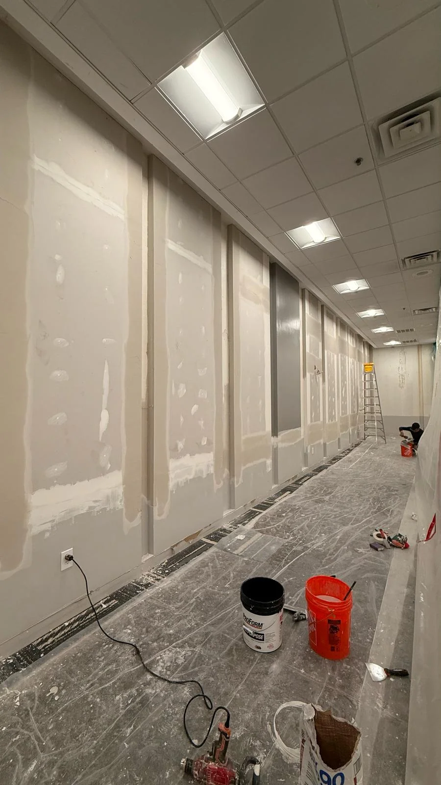 Joint compound applied along drywall seams with tools and floor protection still in place · Tapestry Collection by Hilton