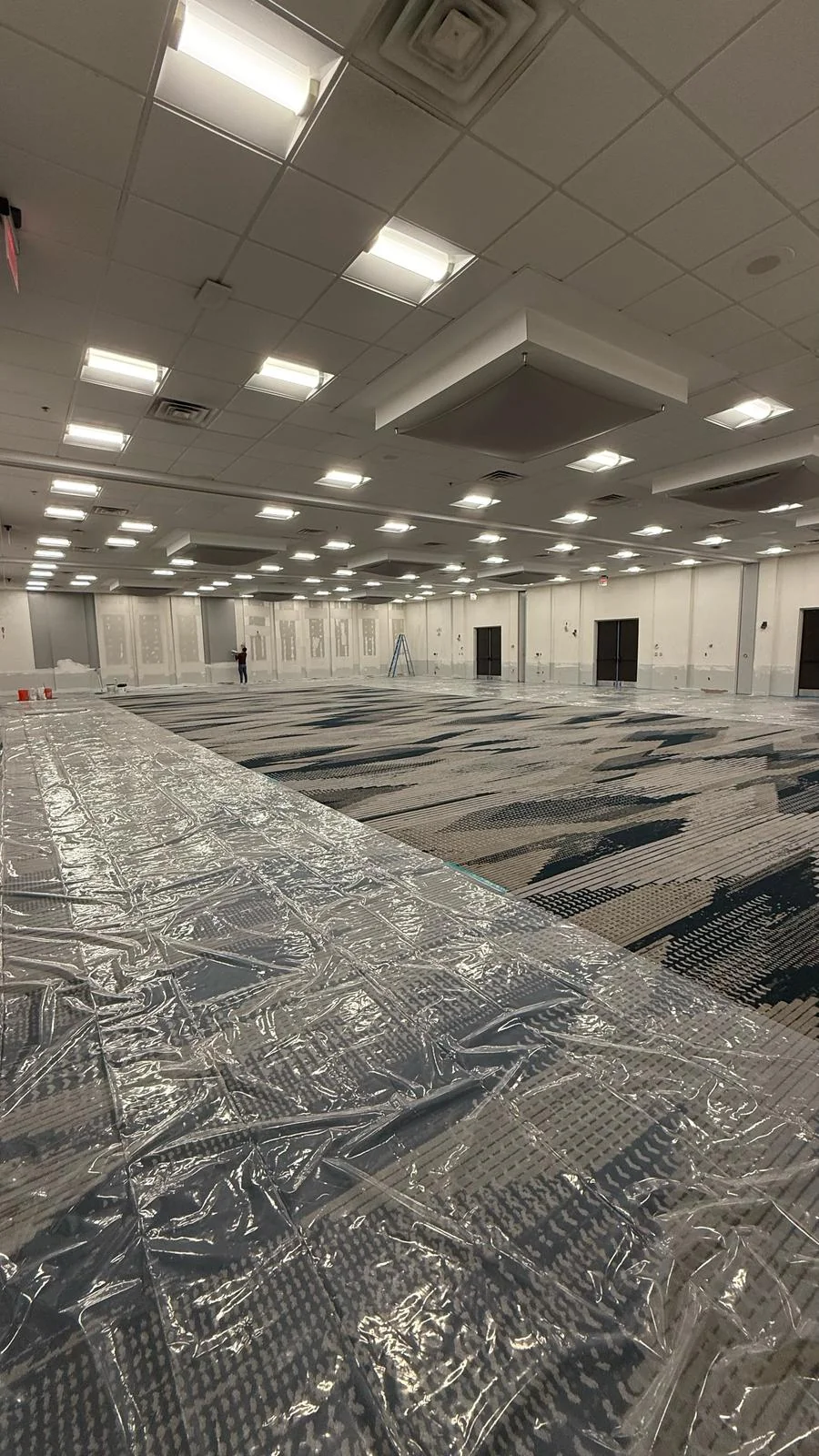 Wide view of the room with wall finishing in progress and protective sheeting over the floor · Tapestry Collection by Hilton