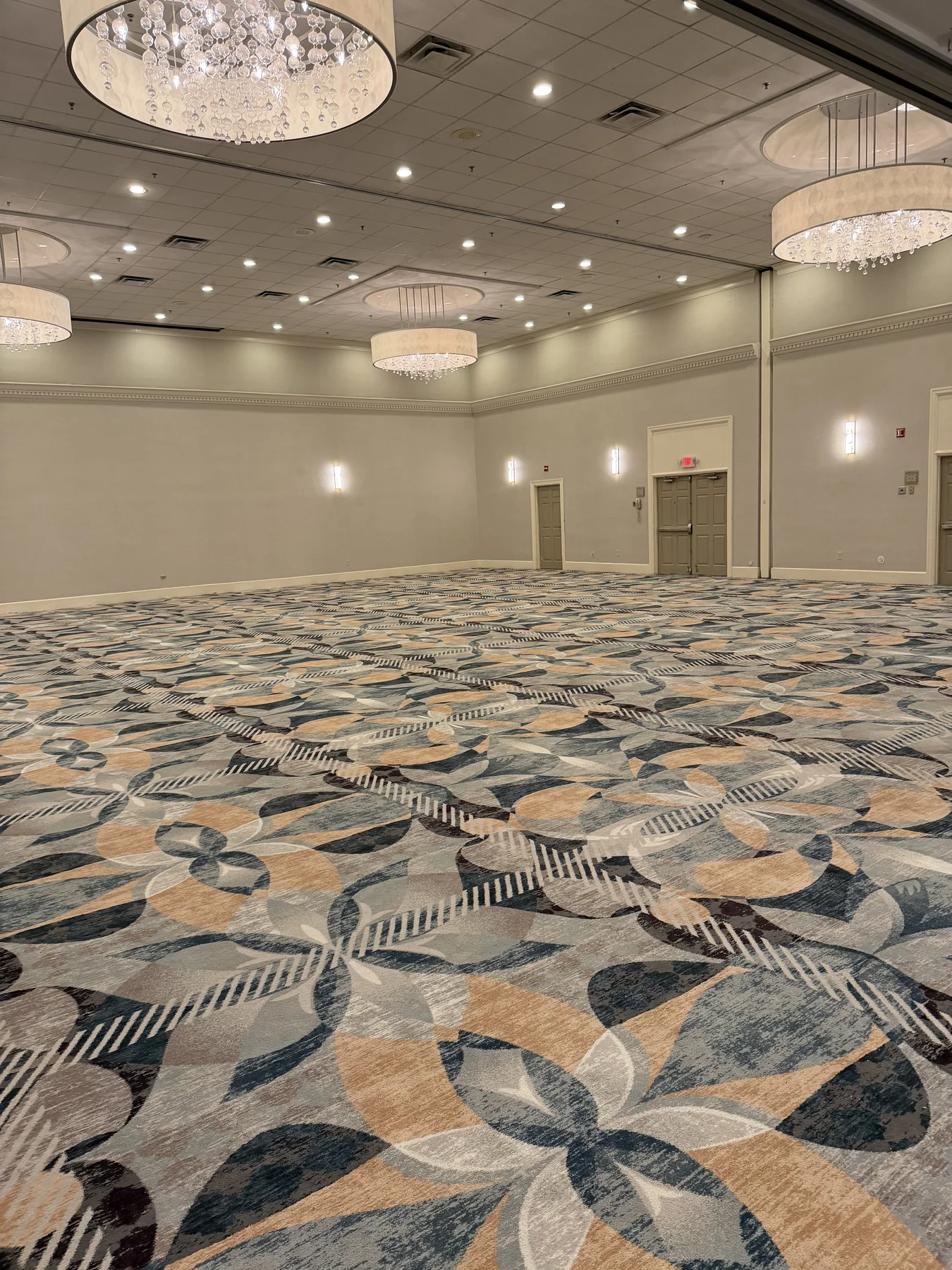 Installed geometric patterned carpet across the DoubleTree by Hilton ballroom, beneath crystal chandeliers