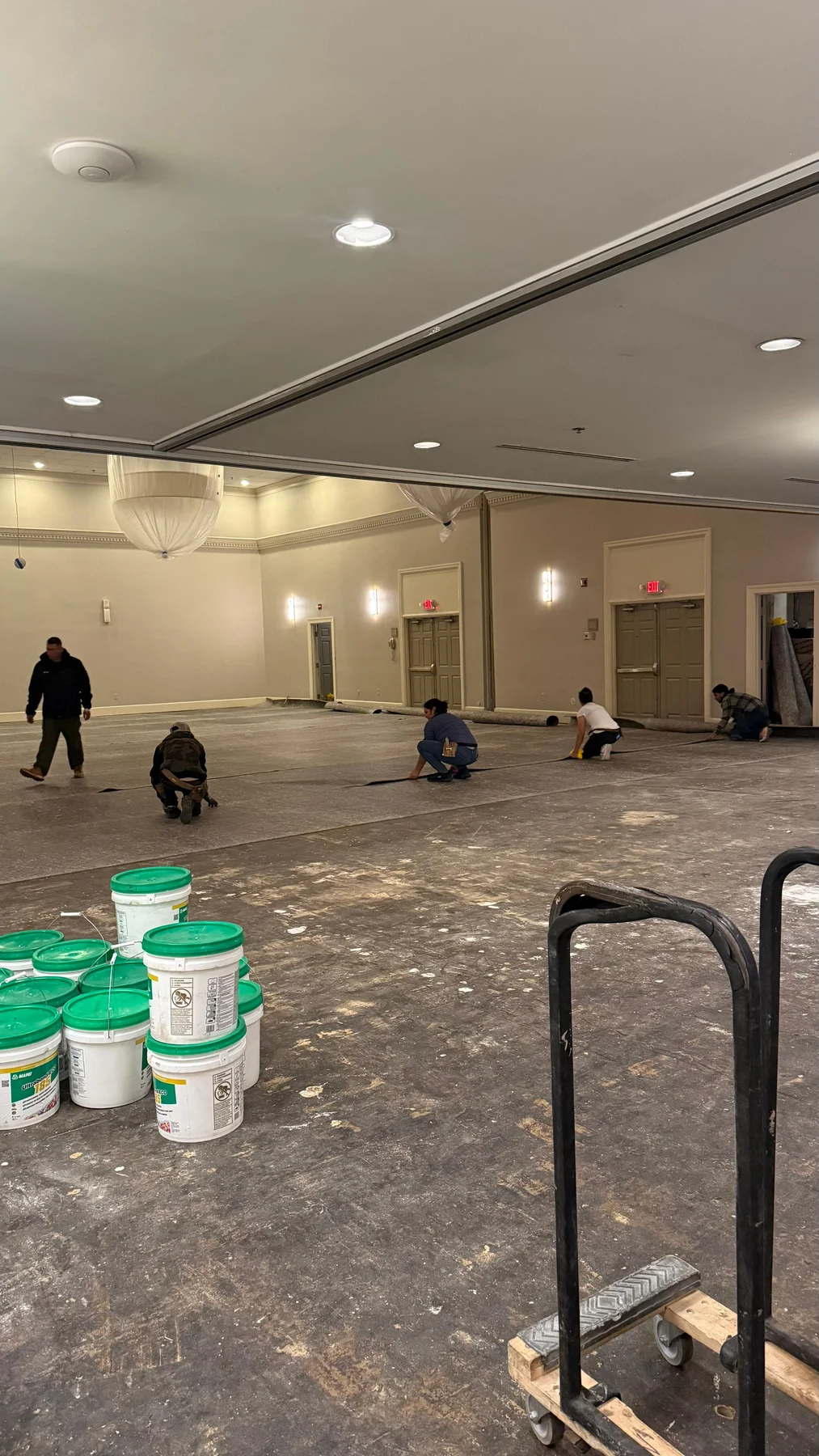 Crew laying the underlayer across the exposed ballroom floor at DoubleTree by Hilton