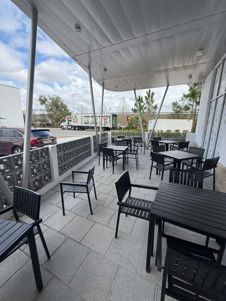 Covered outdoor dining area with tables, chairs and a breeze-block enclosure at Dom Helio Restaurant